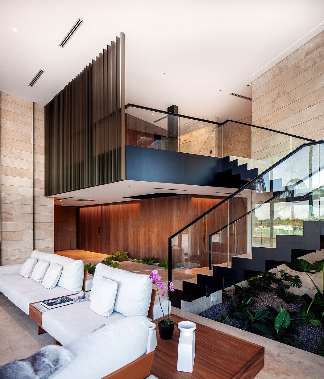 A modern, open-plan living space with sleek wooden cabinetry, glass walls, and a sculptural staircase.