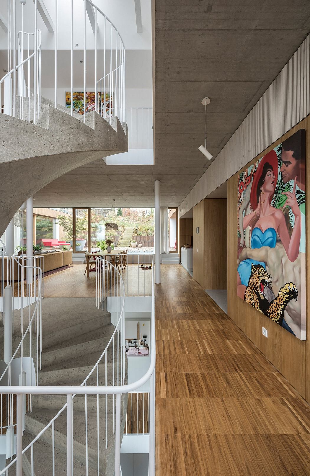 A modern open-plan interior with a concrete spiral staircase and a vibrant mural.