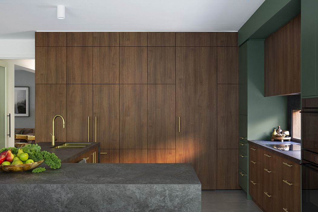 Sleek modern kitchen with dark wood cabinetry, brass fixtures, and gray stone countertops.