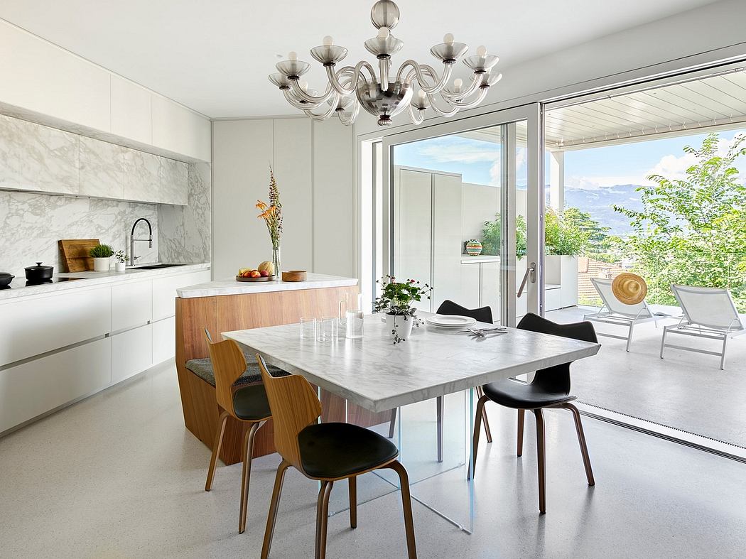 Modern kitchen with marble countertops, sleek cabinets, and a chandelier over the dining area with city views.