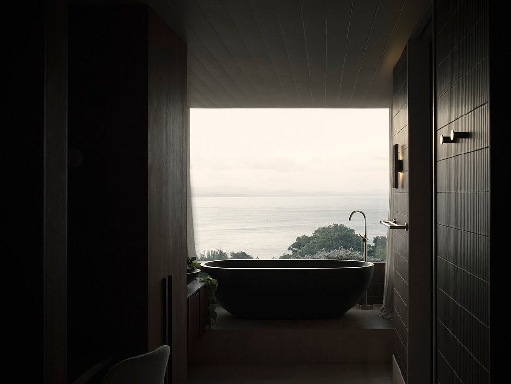 Minimalistic bathroom with freestanding black bathtub overlooking the serene ocean view.