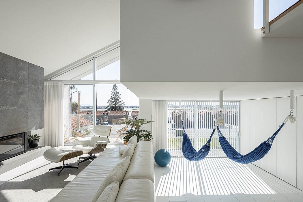 Spacious living room with floor-to-ceiling windows, sleek furniture, and hammocks.