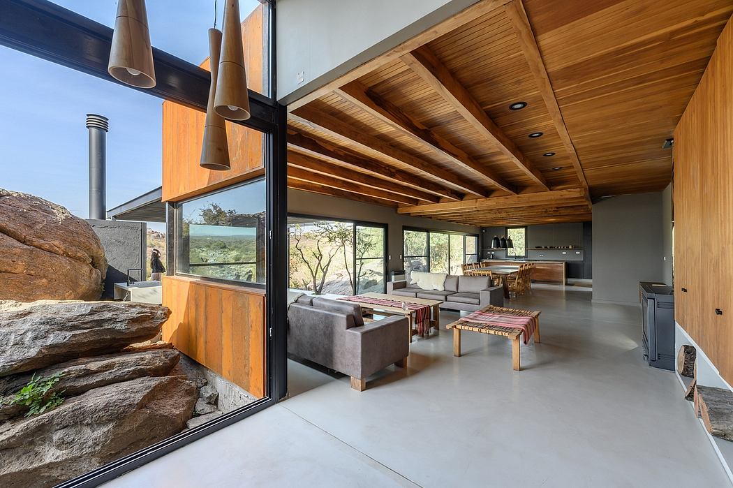 Spacious open-concept interior with vaulted wood-panel ceiling, glass walls, and modern furnishings.