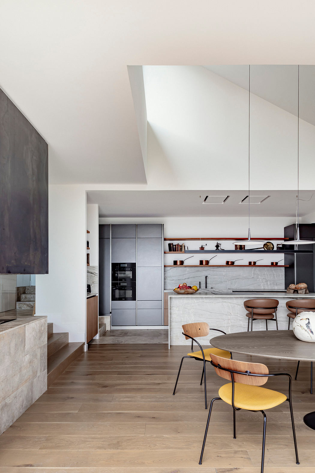 Sleek, modern kitchen with gray cabinets, open shelves, and a round wood dining table.