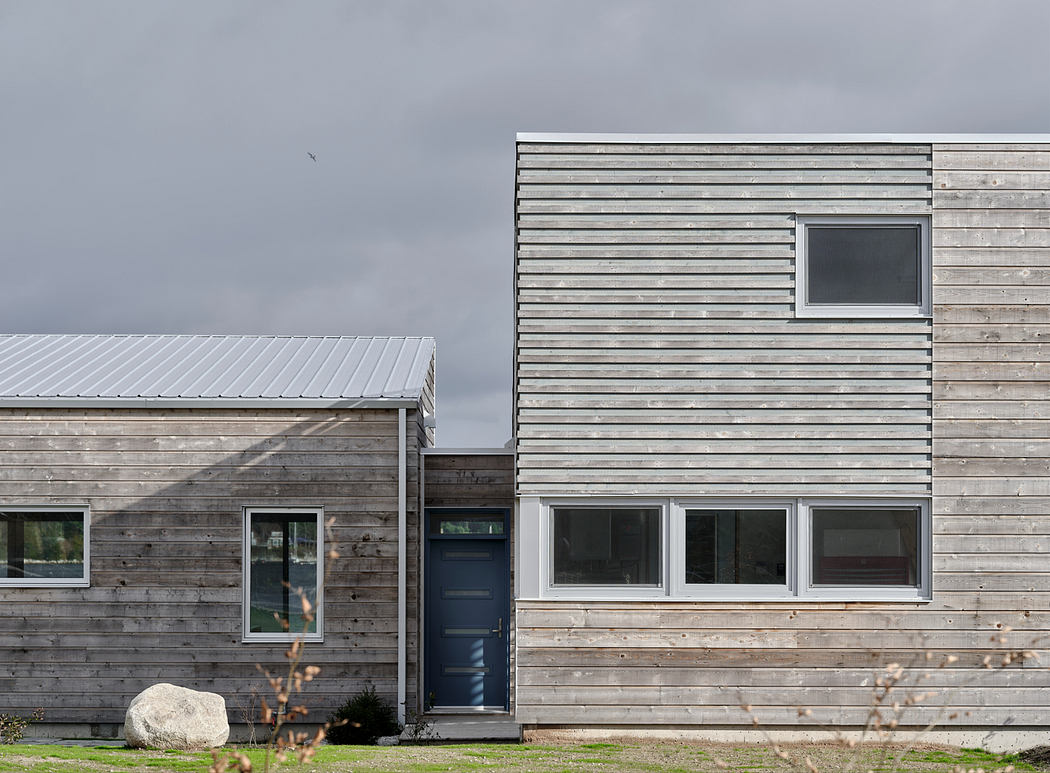 Weathered wood siding, metal roof, and large windows on a contemporary residential building.