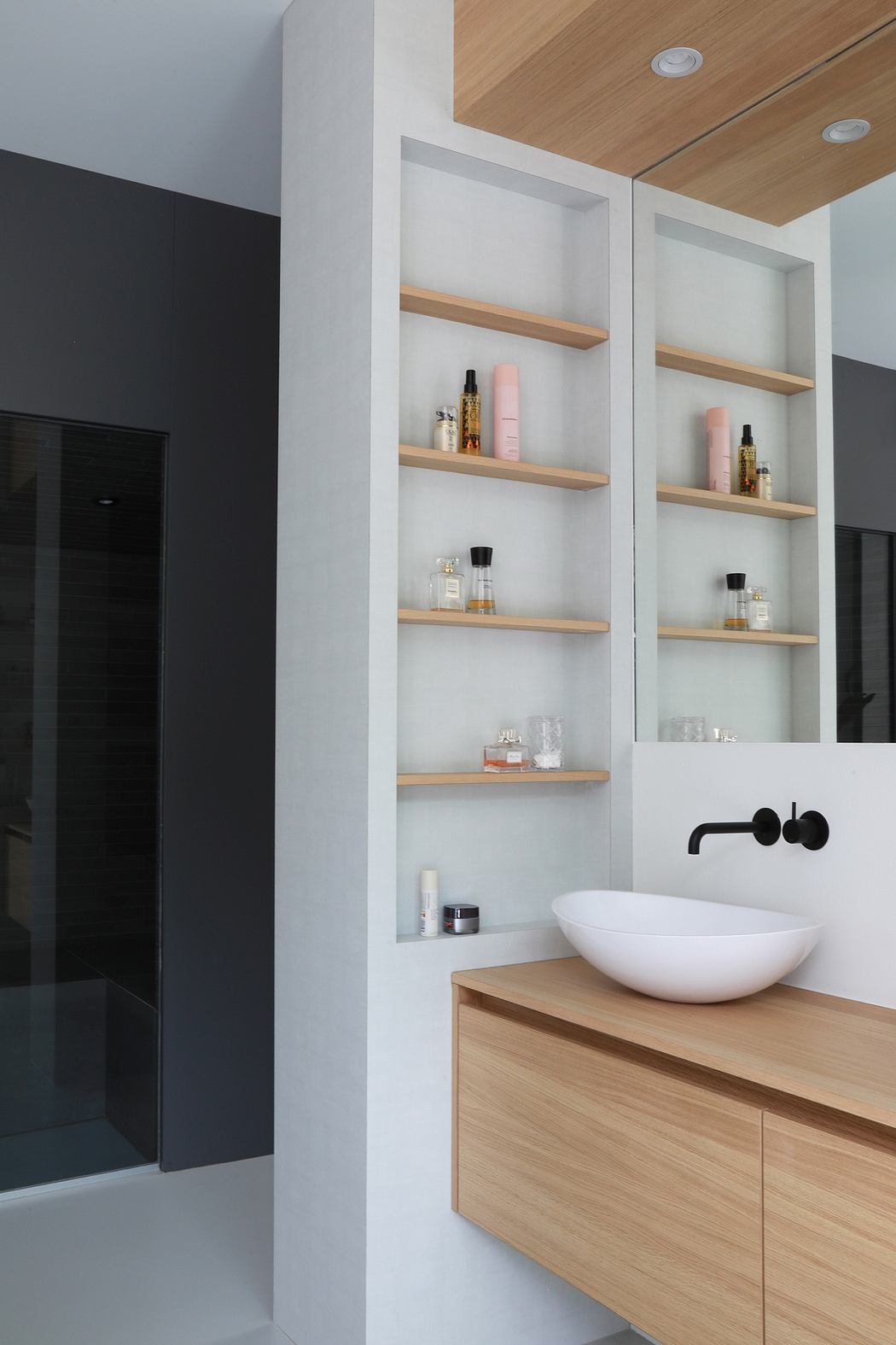 Contemporary bathroom with wooden shelving, vessel sink, and sleek black faucet.