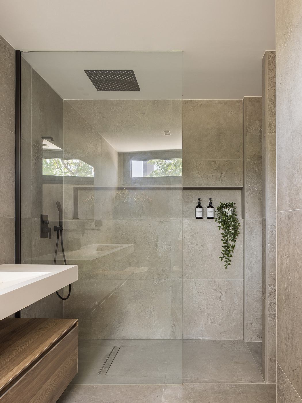 Minimalist modern bathroom with warm wood accents and a large walk-in shower.