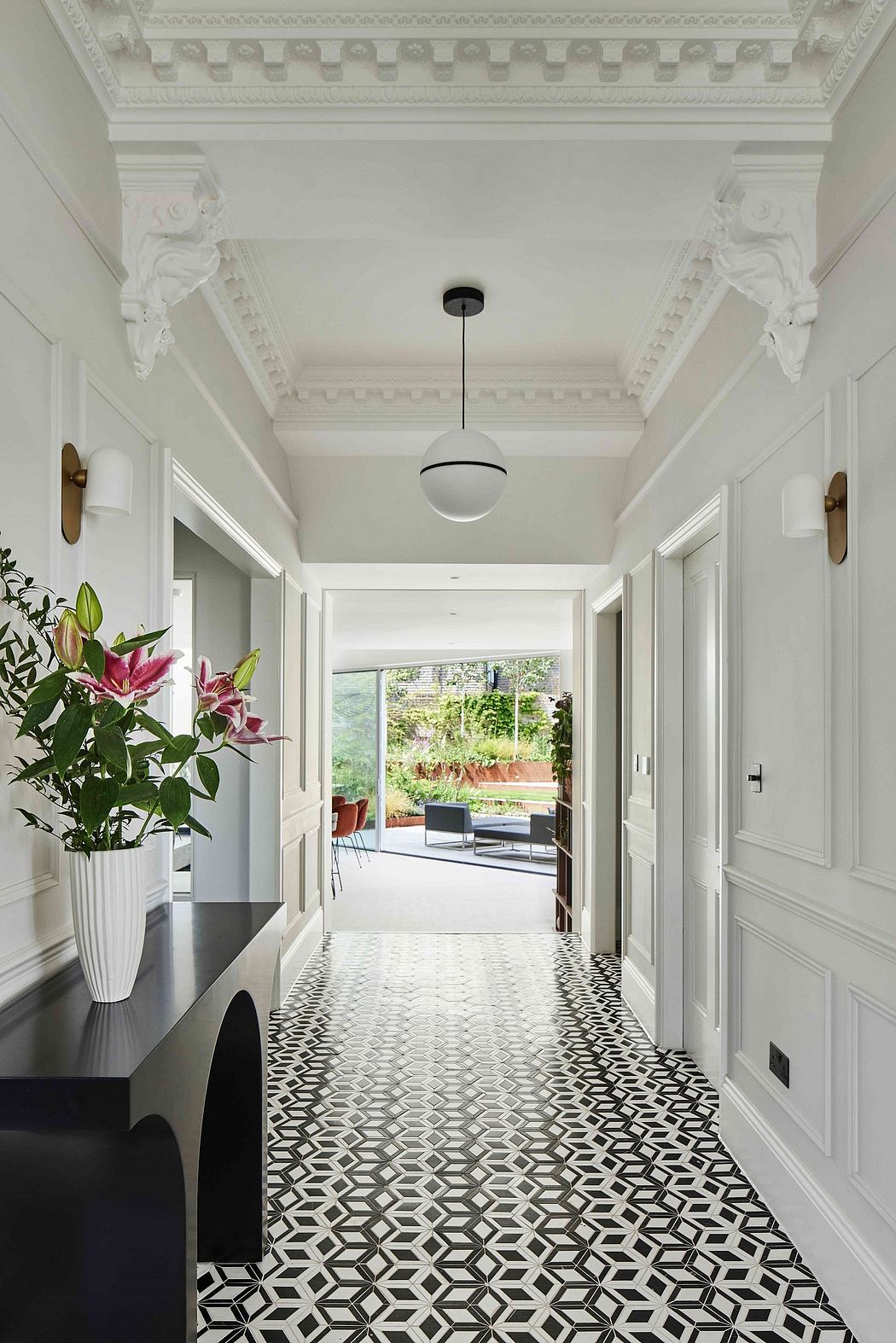 Elegant hallway with decorative ceiling moldings, patterned tile floor, and view to outdoor space.