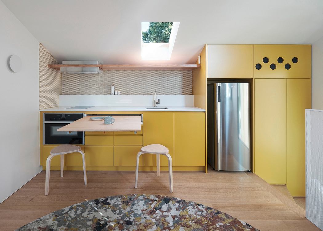 Bright, modern kitchen with yellow cabinets, wood floors, and an interesting abstract rug.
