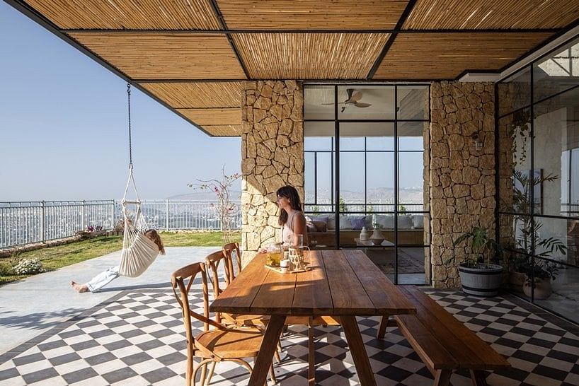 Spacious outdoor terrace with wooden beams, stone walls, and checkered tile floor.