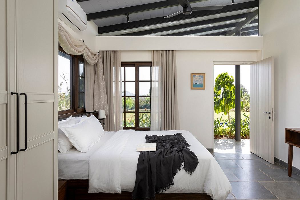 Spacious bedroom with high ceilings, wooden beams, and French doors leading to lush greenery.