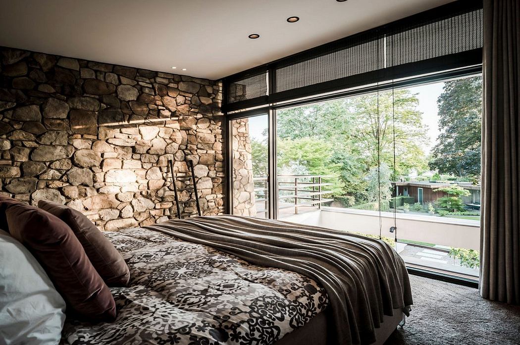 Rustic stone walls, floor-to-ceiling windows, cozy bedding in a modern bedroom design.