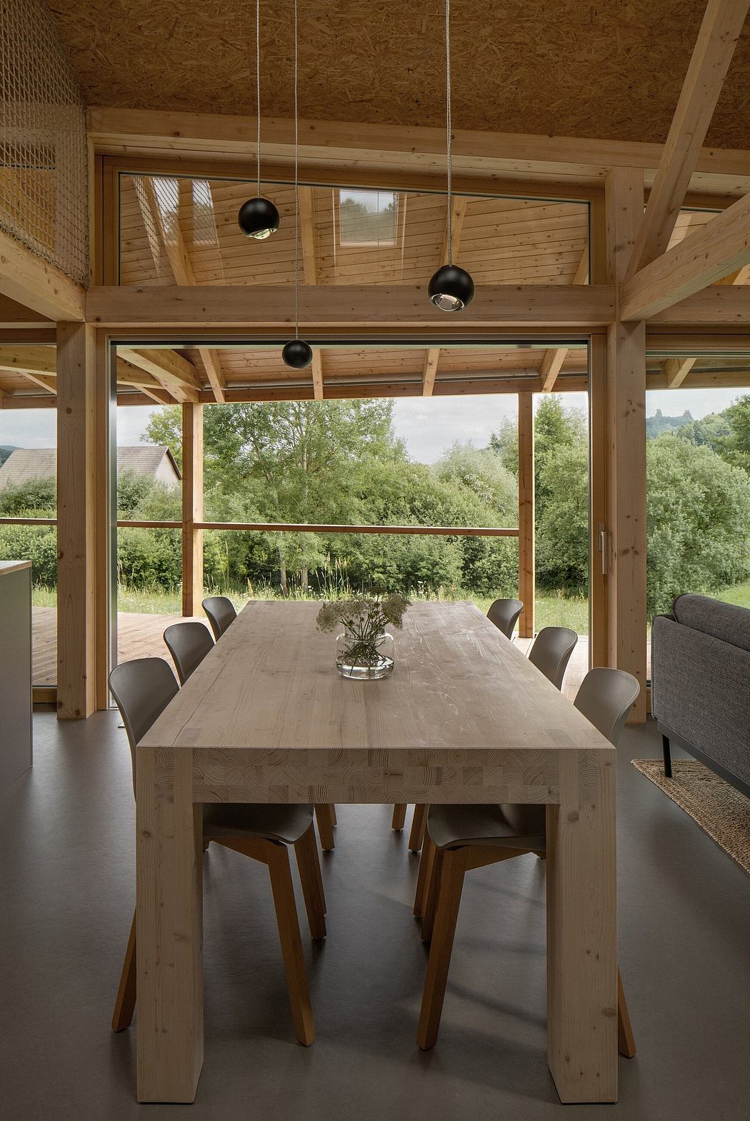 Rustic wooden dining room with modern pendant lights and panoramic forest view.