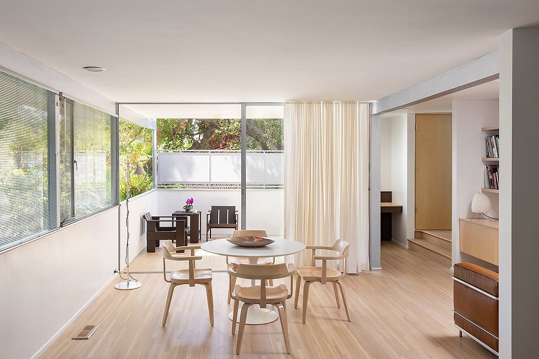 Airy living space with floor-to-ceiling windows, minimalist furniture, and warm wood tones.