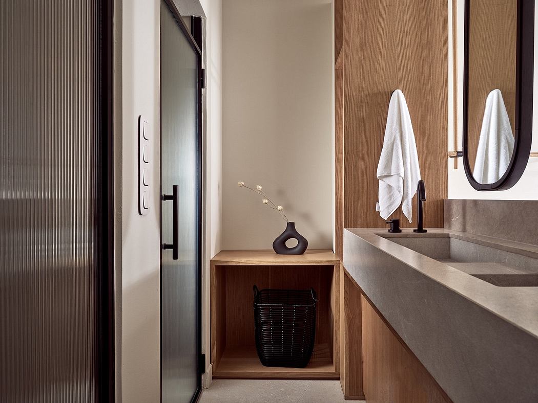 Modern bathroom with wooden vanity, concrete sink, and minimalist decor.