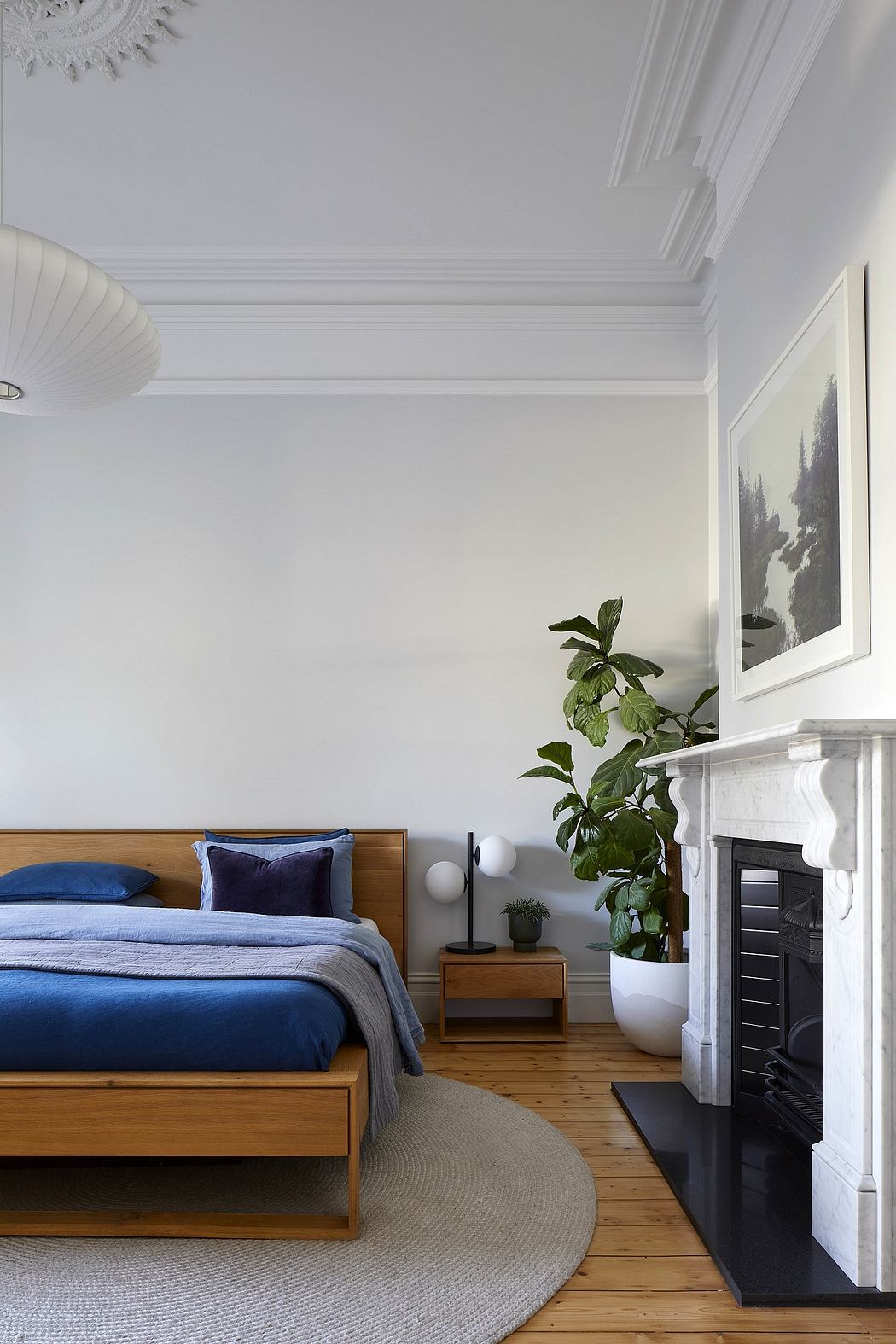 Spacious bedroom with ornate crown molding, wooden furniture, and potted plant.