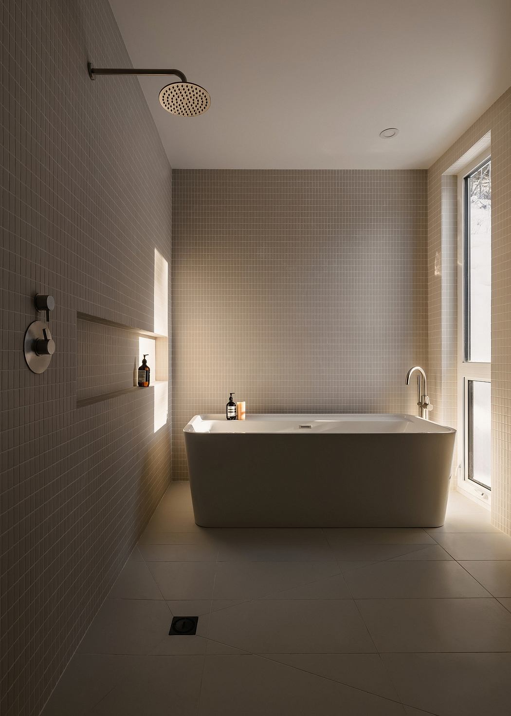 Sleek, minimalist bathroom design with recessed lighting, freestanding tub, and mosaic tile walls.
