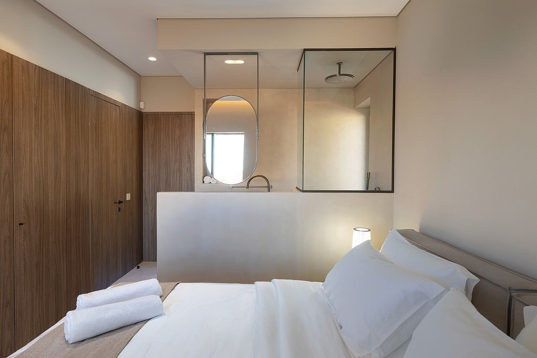 Minimalist hotel room with modern furnishings, sink, and large mirror wall panel.