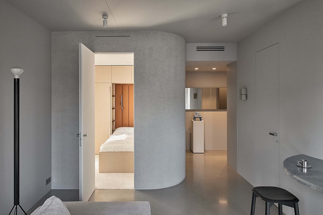 Minimalist interior with neutral tones, curved walls, and built-in furniture.