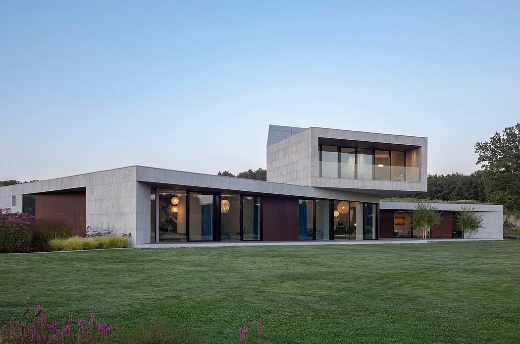 Modern two-story home with concrete walls, large windows, and landscaped yard.