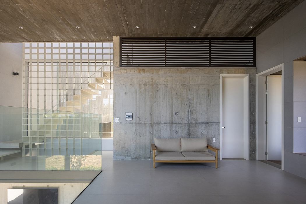 Minimalist interior with concrete walls, glass divider, and mid-century style sofa.