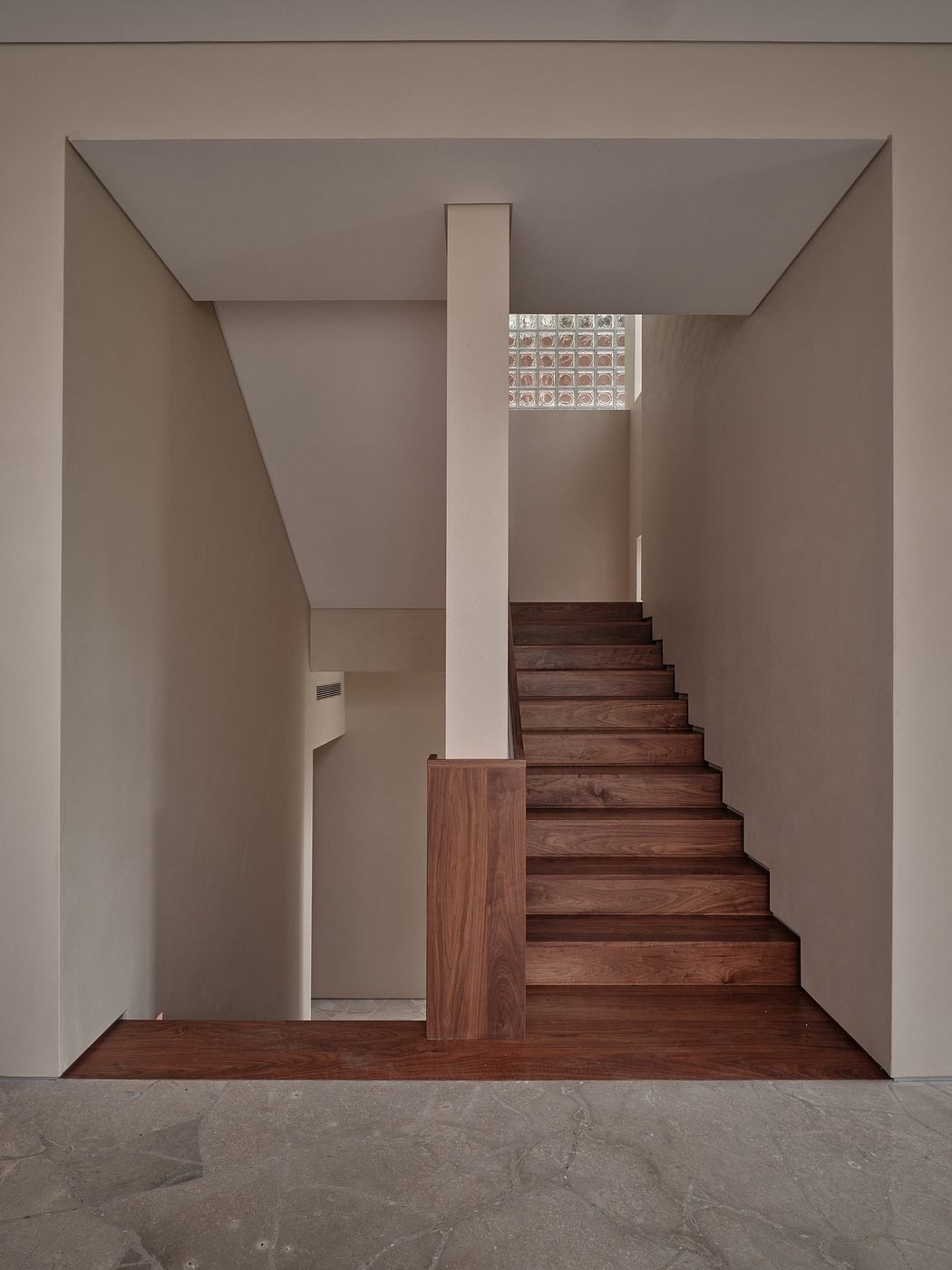 A modern stairway with wooden steps and a geometric glass panel above, set in a minimalist interior.