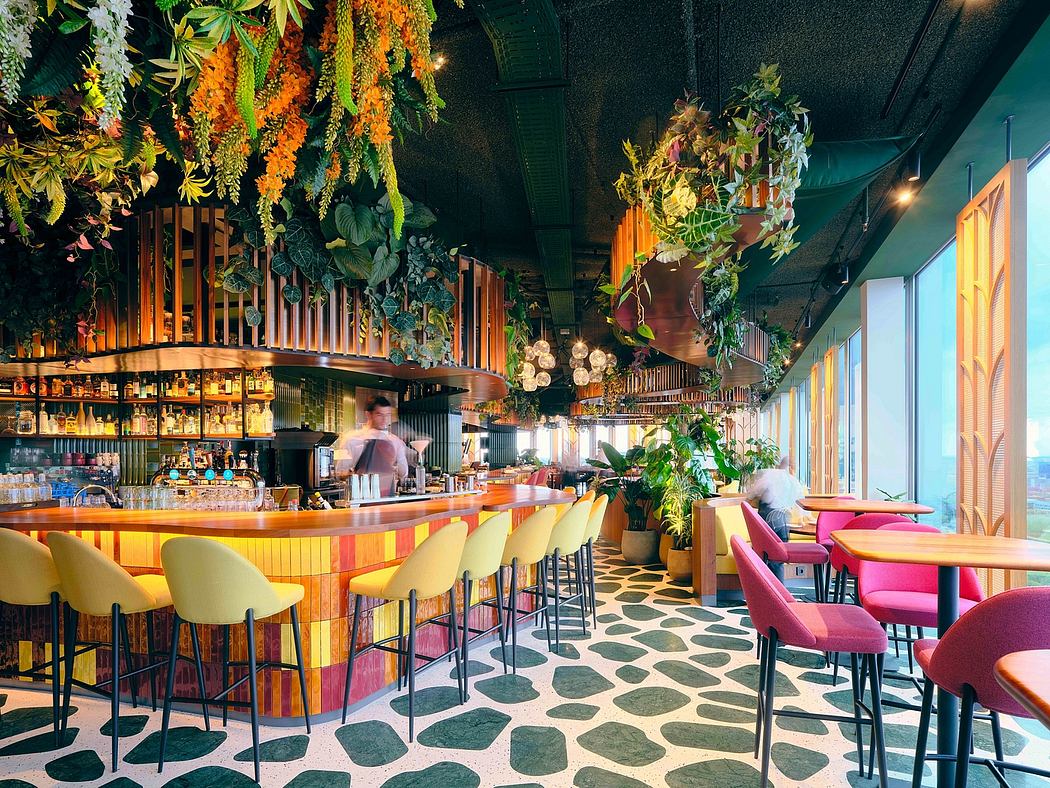 Vibrant, tropically-inspired bar interior with lush foliage, colorful seating, and patterned flooring.