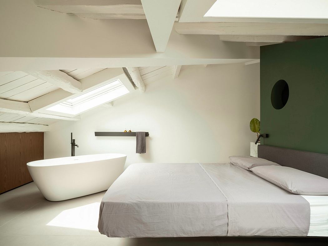 Airy bedroom with freestanding bathtub, modern decor, and natural light from skylights.