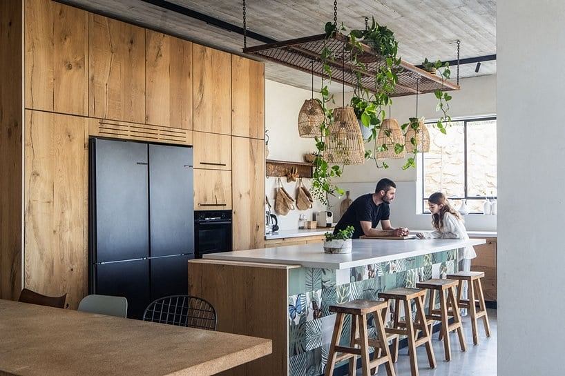 Rustic kitchen with wood paneling, hanging lights, and colorful island decor.