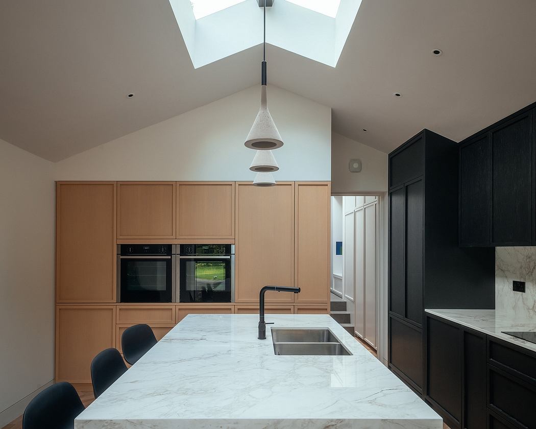 Modern kitchen with wooden cabinetry, marble countertop, and pendant lighting under vaulted ceiling.