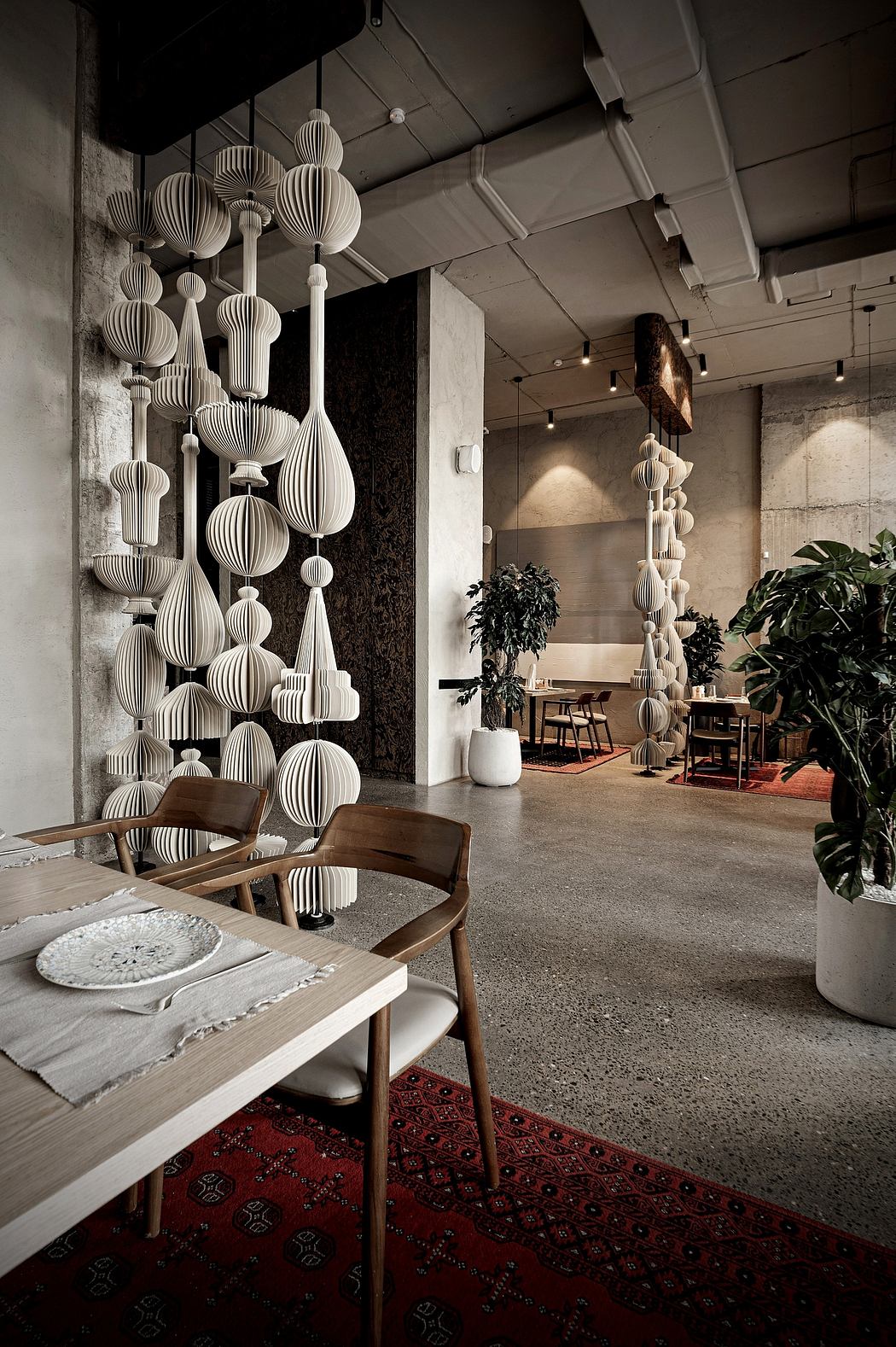 An ornate arrangement of white paper lanterns adorns the ceiling, creating a unique and captivating ambiance in this modern interior space.