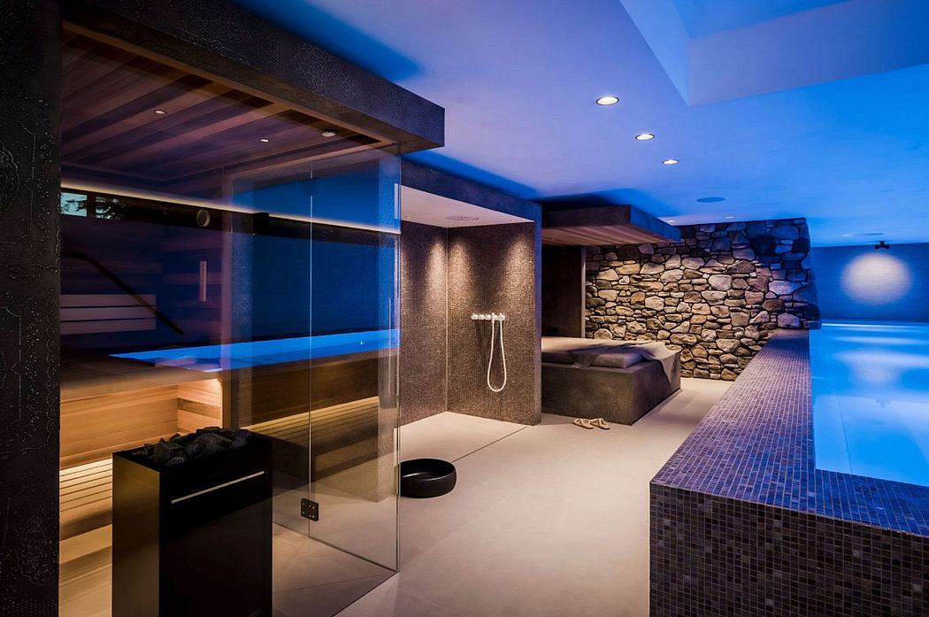 Luxurious spa-like interior with glass-enclosed sauna, mosaic-tiled pool, and rustic stone walls.
