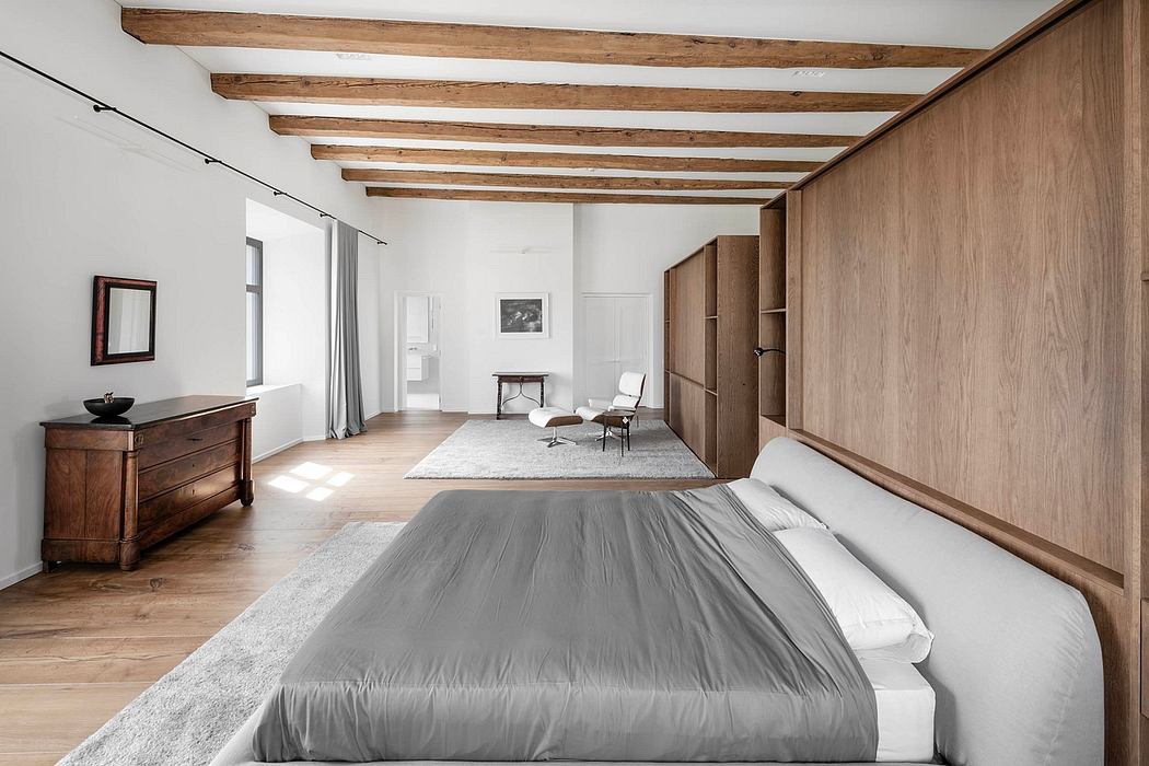 Rustic bedroom with exposed wooden beams, minimalist furniture, and warm lighting.