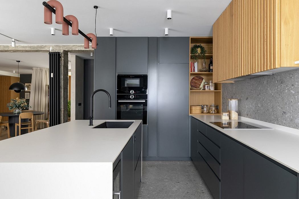A modern kitchen with sleek gray cabinets, a concrete countertop, and a unique lighting fixture.