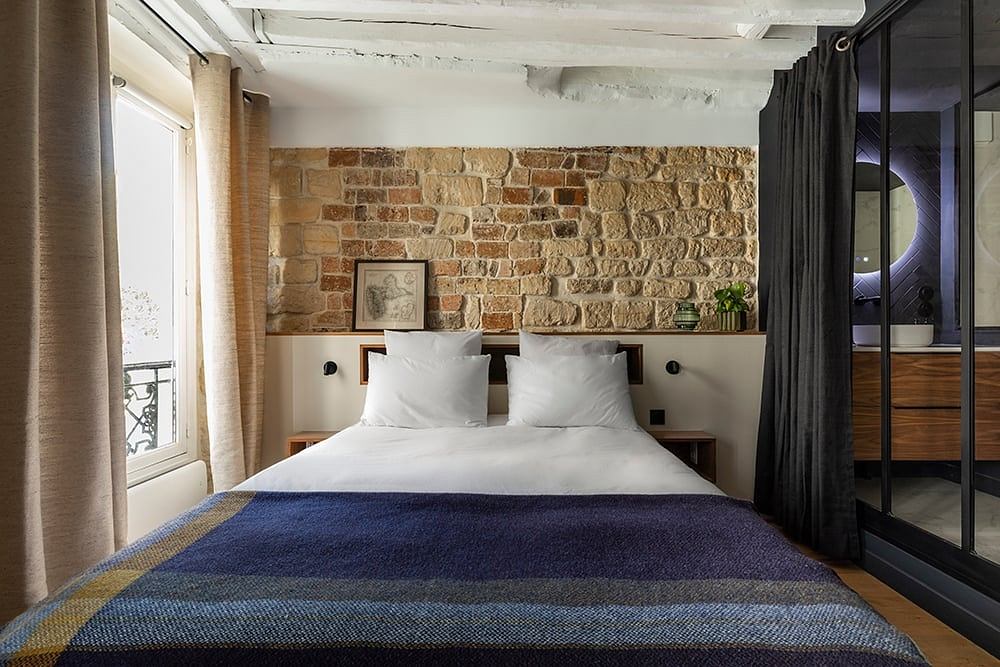 Rustic bedroom with exposed brick wall, wooden accents, and patterned bedding.