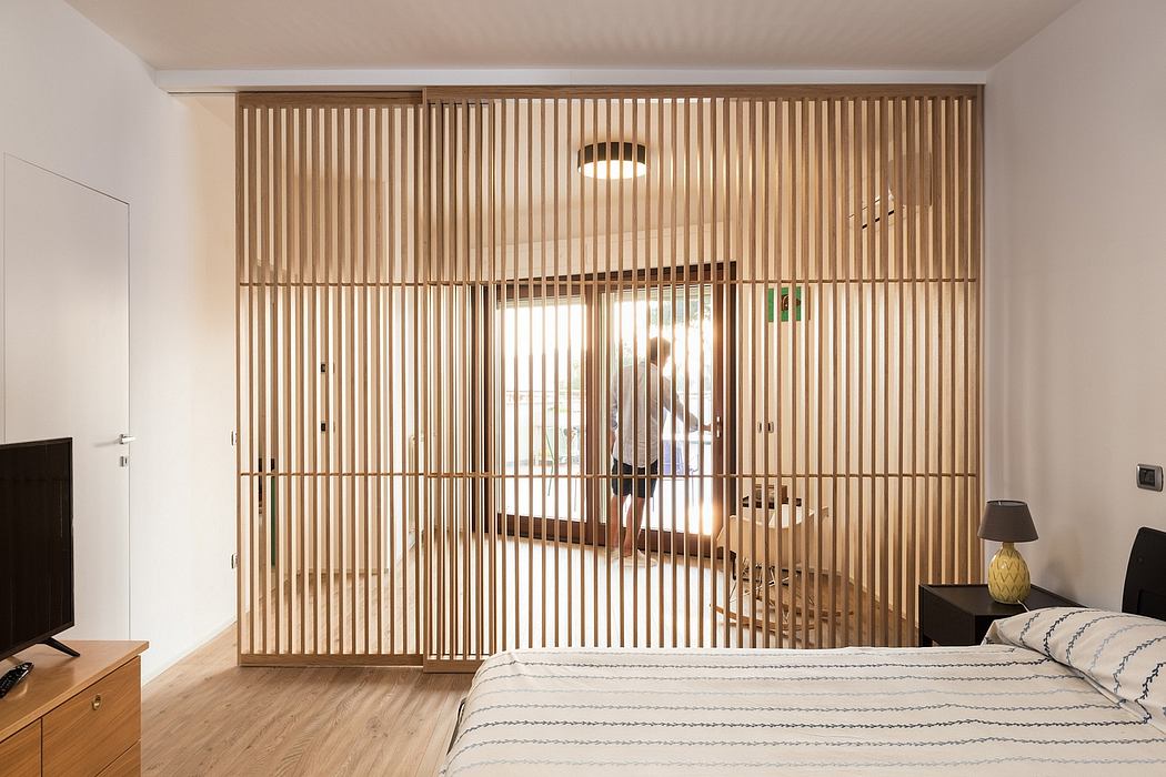 A modern bedroom with a wooden slatted divider that creates visual interest and separates the space.