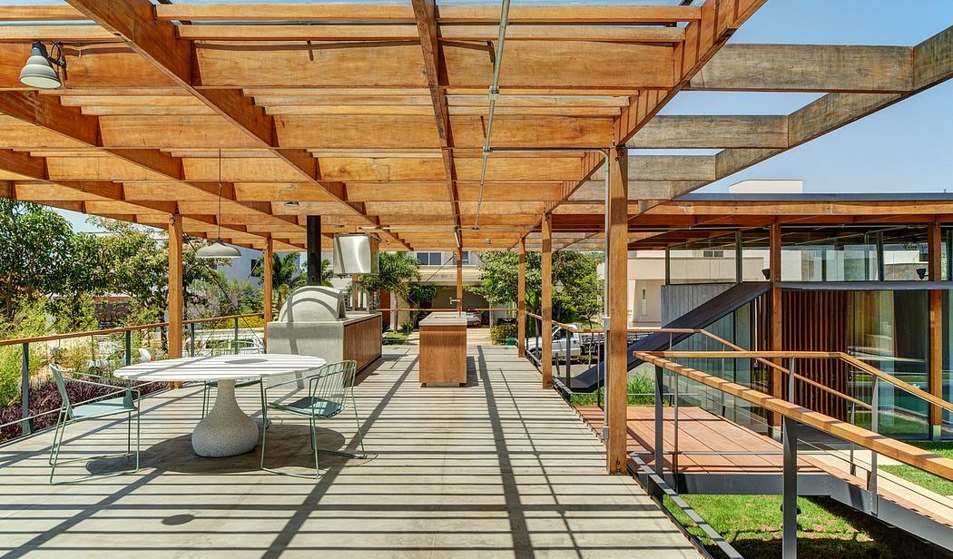 Wooden beams and open-air patio with modern furniture and appliances in a garden setting.