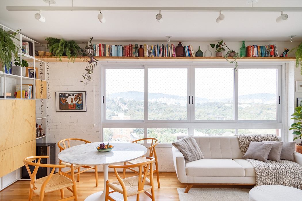 A bright, plant-filled living room with a large window and cozy furnishings.