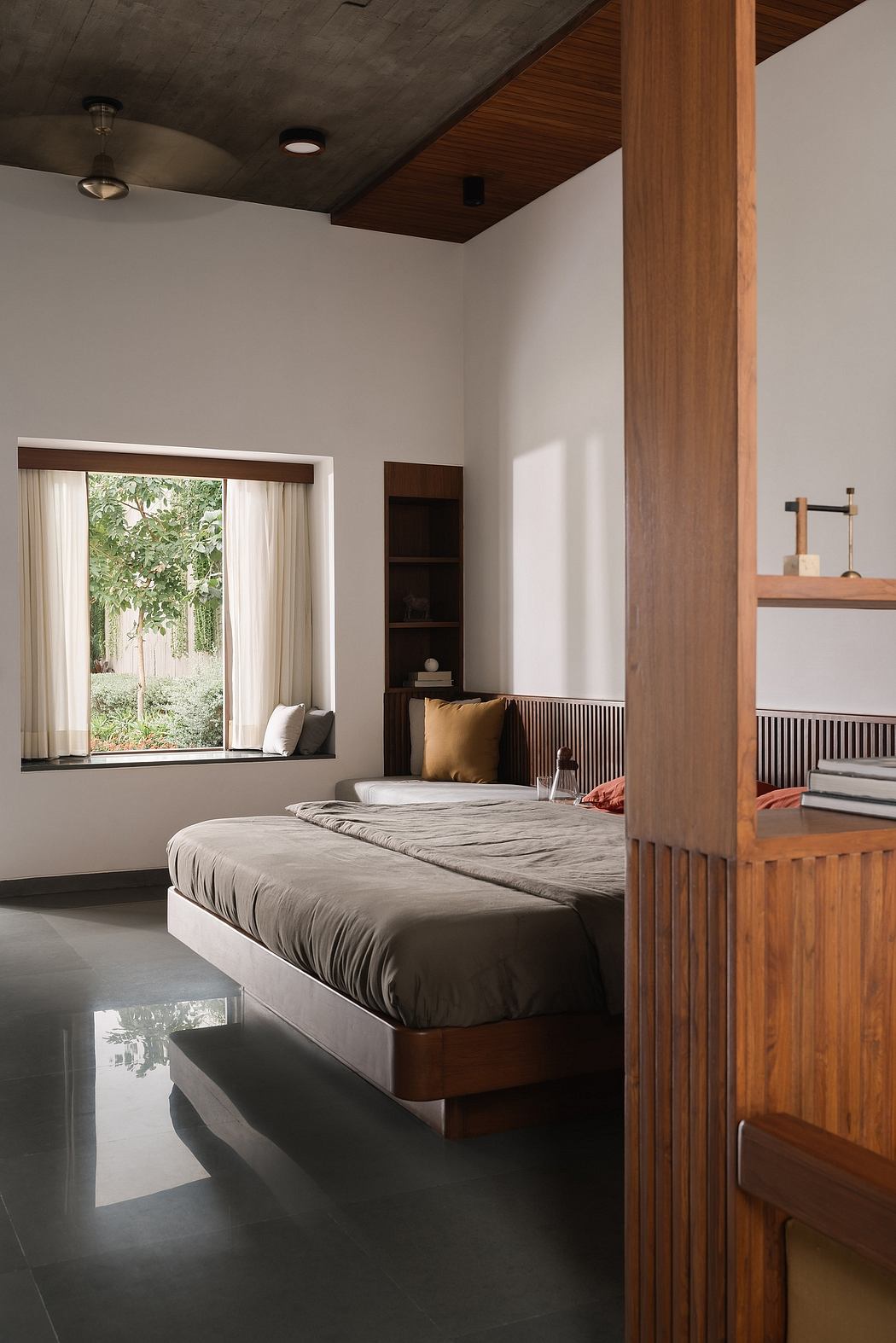Minimalist bedroom with wooden accents, large window overlooking lush greenery.