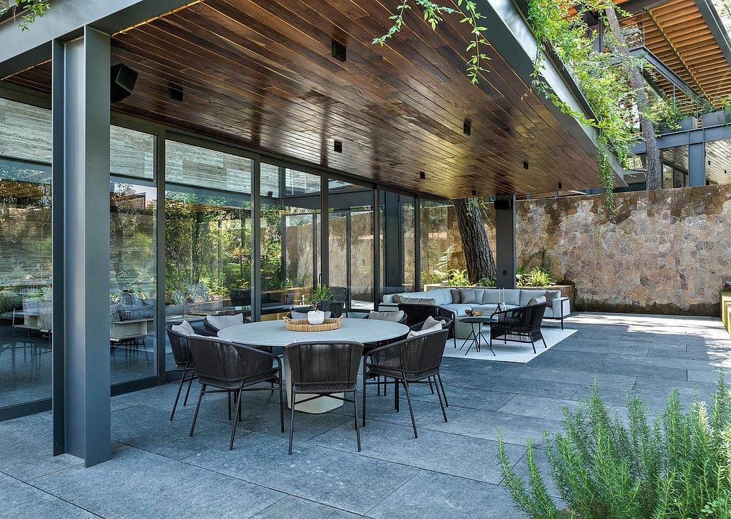 Spacious outdoor patio with modern wooden ceiling, stone walls, and chic furnishings.