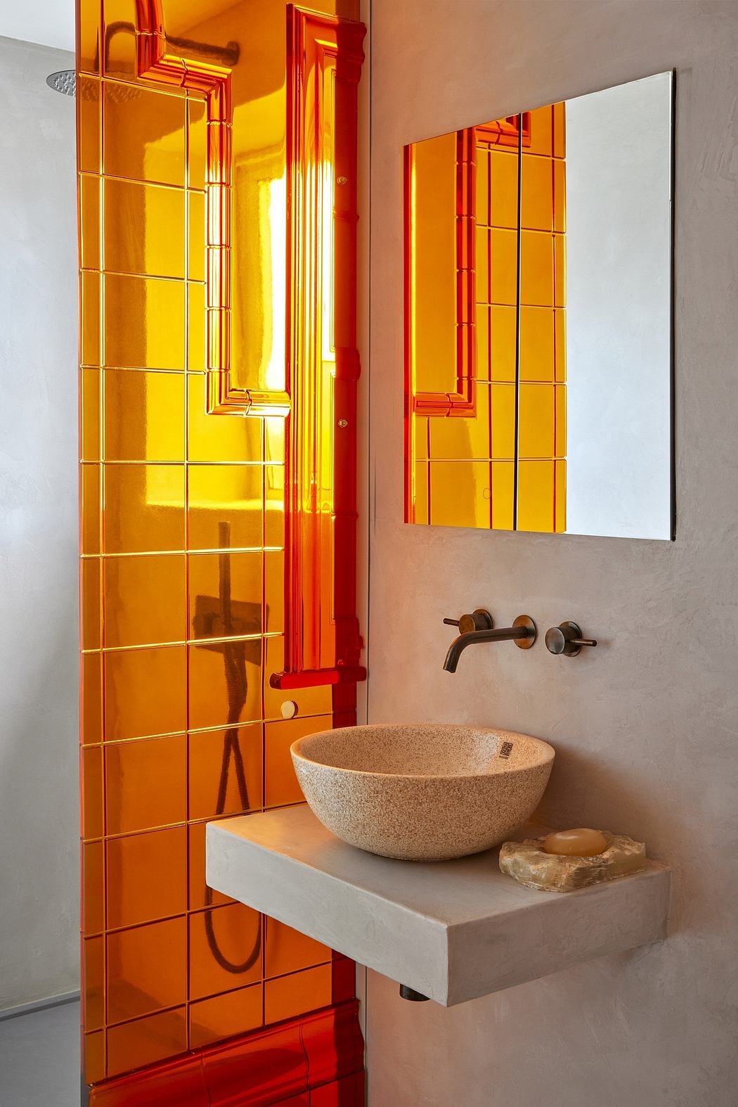 Vibrant bathroom with striking orange tile, minimalist concrete vanity, and natural stone sink.