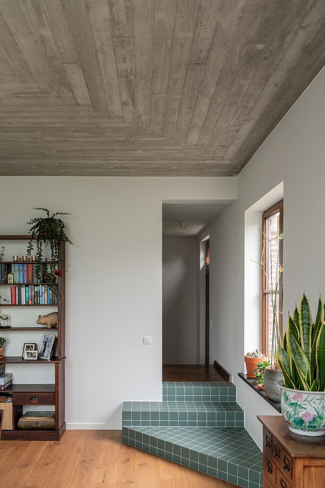 Inviting interior with textured concrete ceiling, tiled staircase, and plant-adorned shelving.
