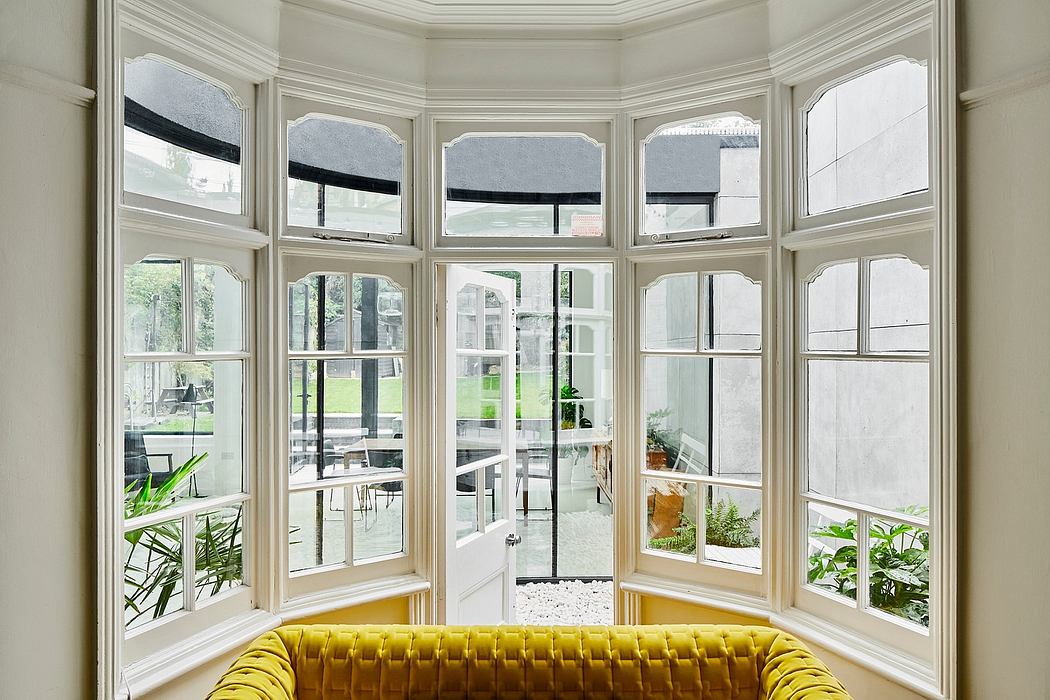Elegant, sun-filled room with arched windows, white walls, and a plush yellow sofa.