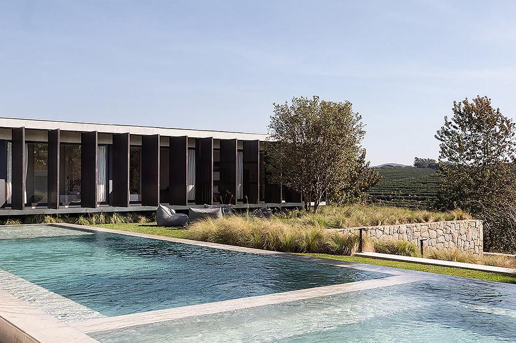 A sleek, modern building with large windows overlooking a scenic pool and landscape.