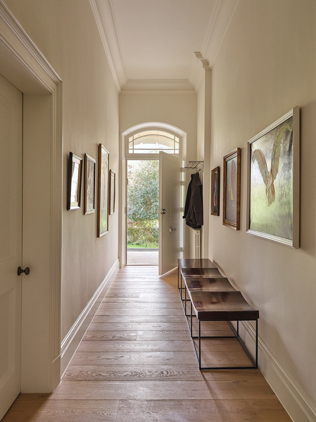 Elegant hallway with arched windows, wooden floors, and framed artwork.