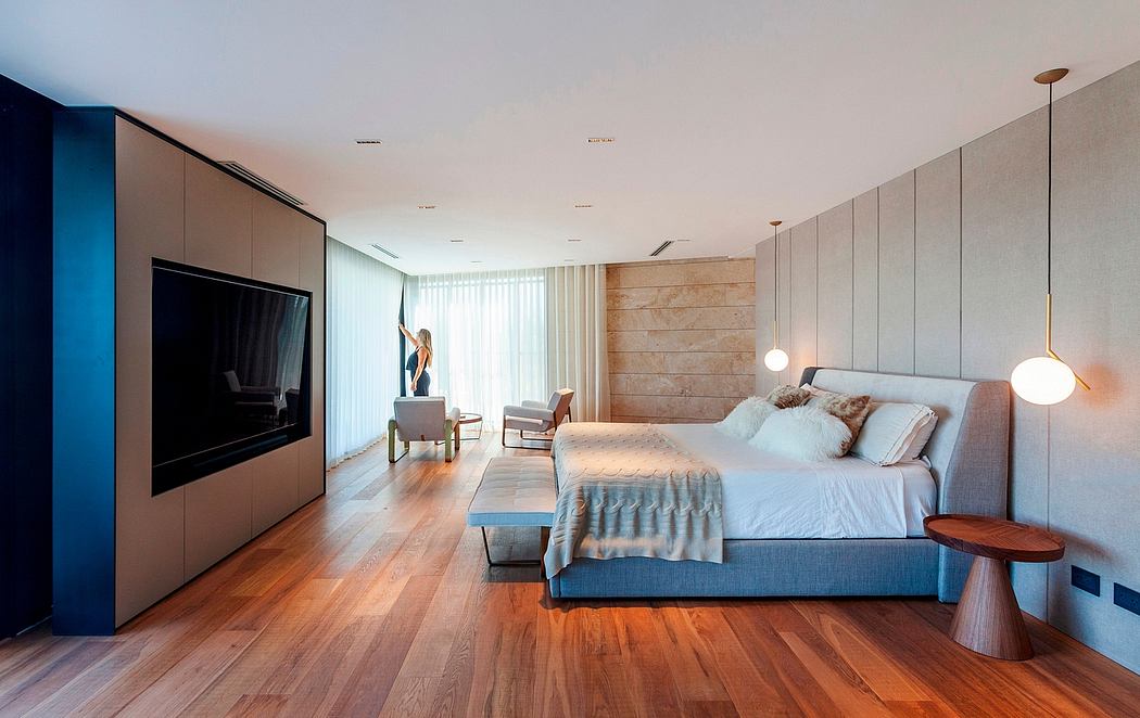 A spacious bedroom with a modern and minimalist design, featuring wood paneling, a large bed, and contemporary lighting.