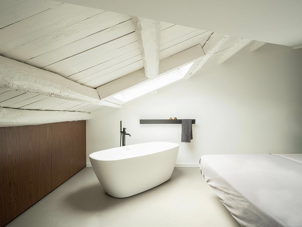 Airy bathroom with white tub, wooden vanity, and exposed wooden beams on vaulted ceiling.