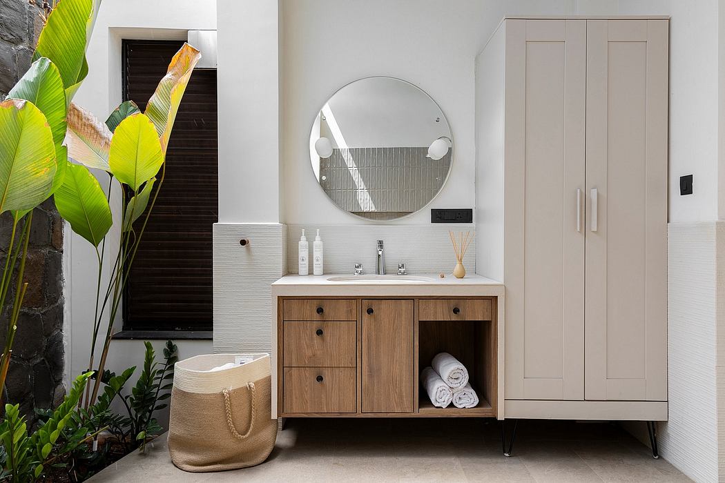Sleek bathroom vanity, round mirror, and modern built-in cabinet against a natural backdrop.