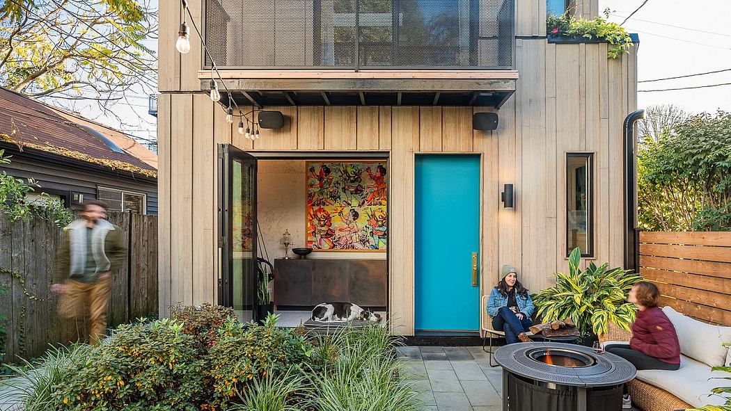 Modern wooden building with vibrant artwork, turquoise door, and cozy outdoor seating.