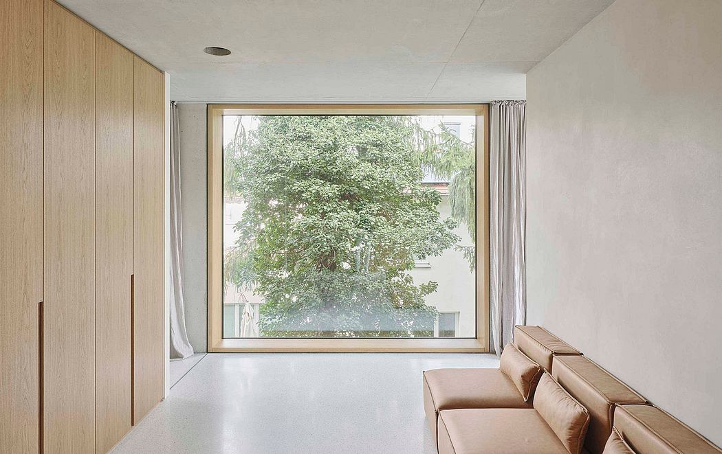 Minimalist living room with large window providing natural views of lush greenery.